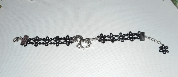 Original pulsera con caballo de metal plateado sobre encaje negro