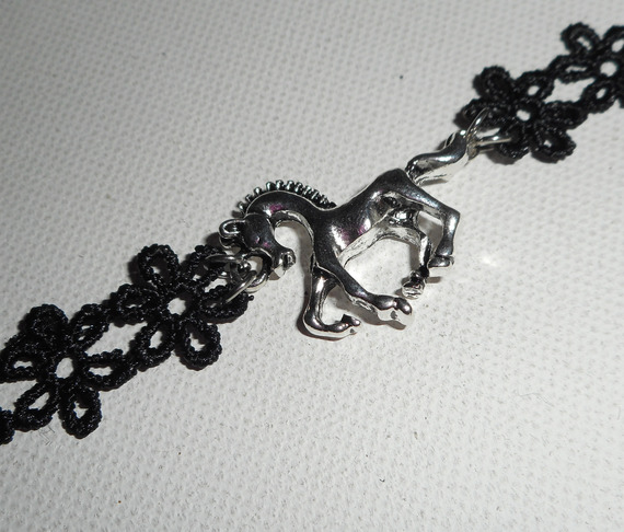 Original pulsera con caballo de metal plateado sobre encaje negro