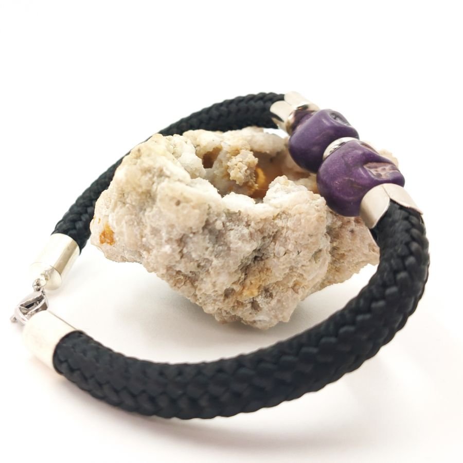 Pulsera doble de calavera y tibias cruzadas con piedras moradas sobre cuerda negra