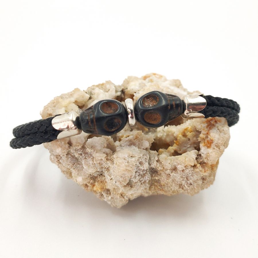 Pulsera doble de calavera y tibias cruzadas con piedras negras sobre cuerda doble