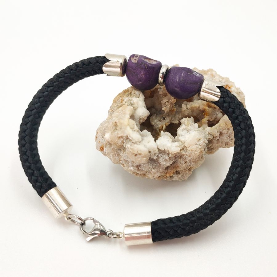 Pulsera doble de calavera y tibias cruzadas con piedras moradas sobre cuerda negra