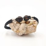 Pulsera doble de calavera y tibias cruzadas con piedras negras sobre cuerda doble